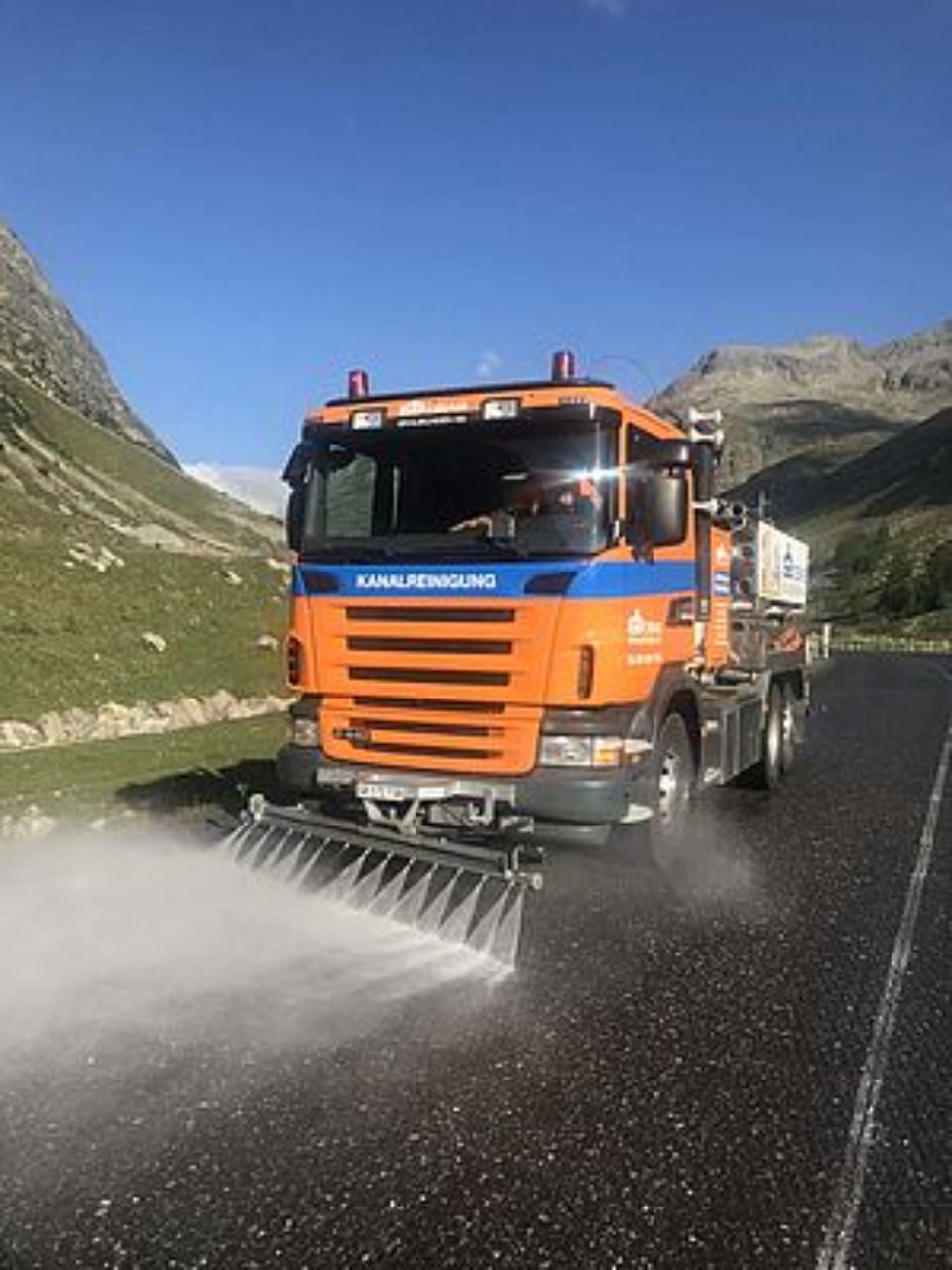 Reinigungsfahrzeug der OBAG Graubünden AG säubert Strasse mit Wasserstrahlen